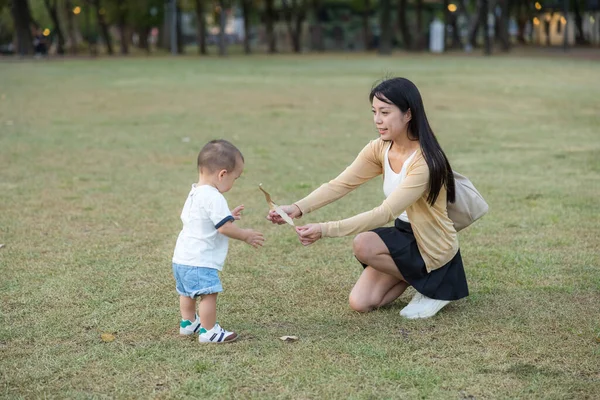 Anne yeşil çimlerde bebekle oynuyor.