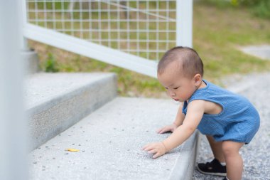 Küçük çocuk dışarıda taş merdivenlerde sürünmeye çalışıyor.