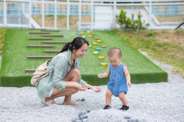 Bebek parkta annesiyle mutlu bir şekilde oynuyor.