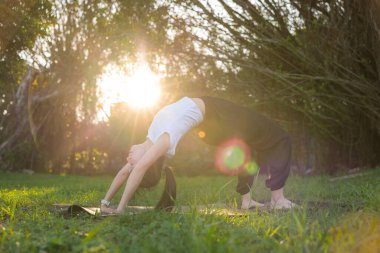 Dışarıda gün ışığında yoga yapan bir kadın.