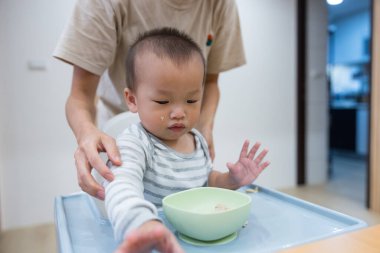 Anne bebeğe elleriyle yemek yemeyi öğretiyor.