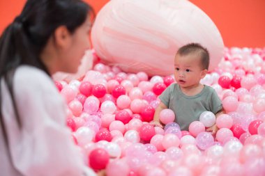 Neşeli anne ve bebek renkli top havuzunda kaynaşıyor