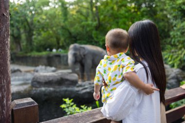 Anne fil bakarken bebeği tutuyor.