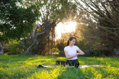 Spor kadın parkta akıllı saatini kontrol ediyor.