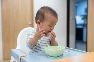 Mutlu bebek içeride yüksek sandalyede yemek yiyor.