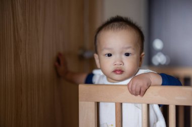 Bebek beşikte durmuş etrafa mutlu bir şekilde bakıyor.