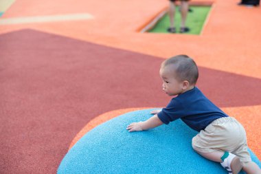 Küçük çocuk dışarıda oyun parkında oynuyor ve tırmanıyor.