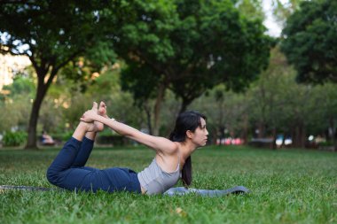 Spor yapan kadın parkta yoga yapıyor.