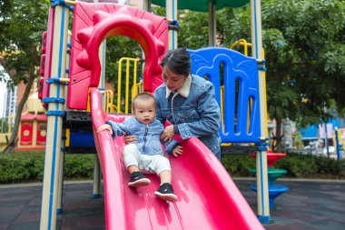 Mutlu anne ve bebek oyun parkında birlikte oynuyorlar.