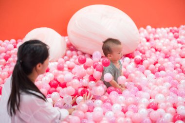 Anne küçük oğluyla pembe top havuzunda oynuyor.