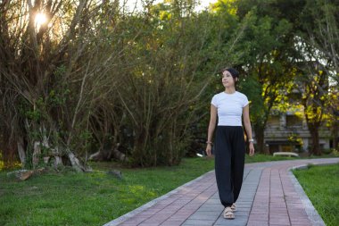 Güzel park doğasında yalnız yürüyen genç kadın.