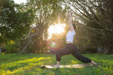 Dışarıda parkta yoga yapan bir kadın.
