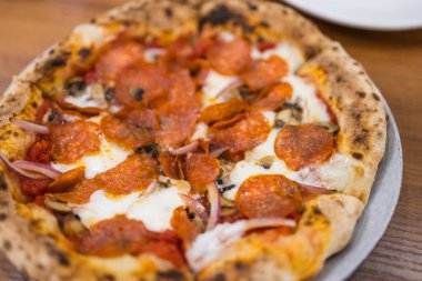 Peynirli ve domatesli baharatlı sosisli pizza.