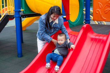 Bebek dışarıda oyun parkında mutlu bir şekilde kayıyor.