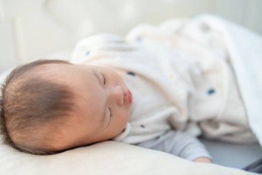 Bebek evdeki yumuşak yatakta huzur içinde uyuyor.