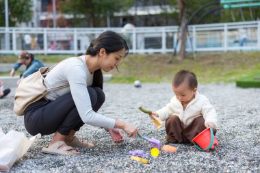 Anne ve bebek parkta çakıl taşlarıyla oynuyor.