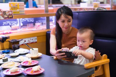 Restoranda bebek telefonu veren bir kadın.