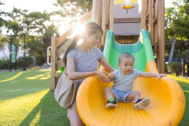 Anne bebeği oyun parkına götürüyor.