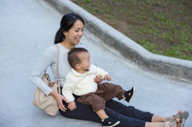 Anne ve bebek birlikte parktan aşağı kayıyor.