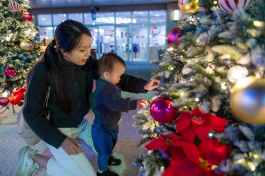 Anne ve bebek birlikte Noel ağacına bakıyor.