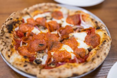 Tahta tabakta servis edilen acılı sosisli pizza.