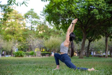 Genç bayan parkta yalnız başına yoga yapıyor.