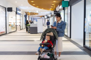Annem bebek arabasında bebekle telefon kullanıyor.