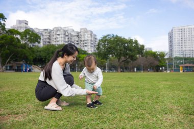 Annem parkta çömelmiş bebekle.