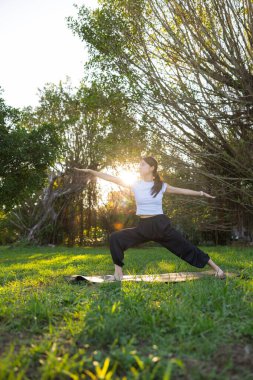 Kadın parkta yoga yapıyor.