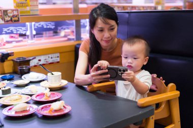 Annem bebeğe restoranda telefon izletmiş.