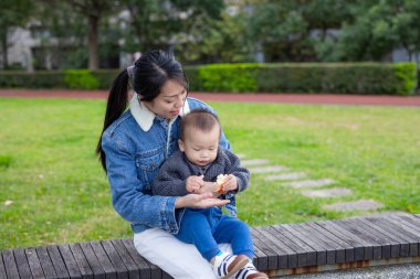 Bebek abur cubur yer ve parkta annesinin üzerine oturur.