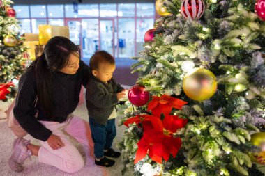 Anne ve bebek Noel ağacını birlikte süslüyorlar.