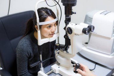 Klinik muayenesi sırasında gözlerini kontrol eden bir kadın.