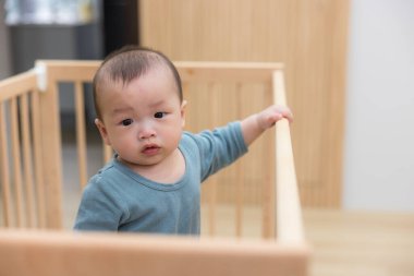 Bebek yatağında bağımsız olarak duran küçük çocuk.