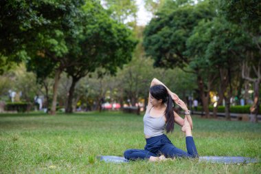Dışarıdaki bahçede yoga yapmaktan hoşlanan bir kadın.