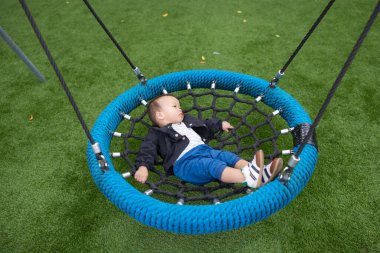 Bebek parkta salıncakta sakince yatıyor.