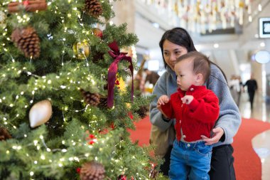 Ebeveynler ve bebekler Noel ağacının tadını çıkarıyor.