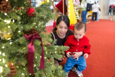 Bebek ve anne Noel ağacı ışıklarının keyfini çıkarıyorlar.
