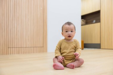 Evin zemininde oturan küçük bebek.