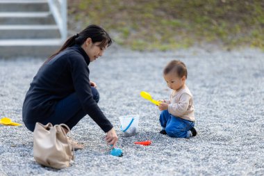 Anne çocuğa çakıl taşlarıyla oynamayı öğretiyor.