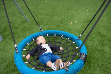 Küçük bebek oyun parkında dinleniyor. Dışarıda sallan.