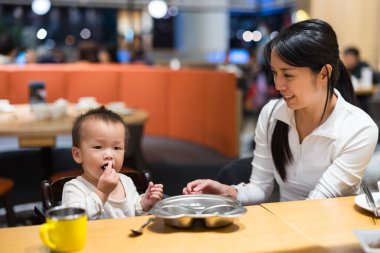 Annesi lokantada yemek yerken bebeği besliyor.