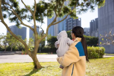 Anne bebeği şehir parkında bir arada tutuyor.