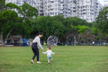 Anne bebeğiyle parkta koşuyor.