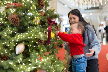 Mother showing baby christmas tree decorations together