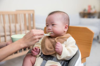 Anne bebeği katı yiyecekle besliyor.