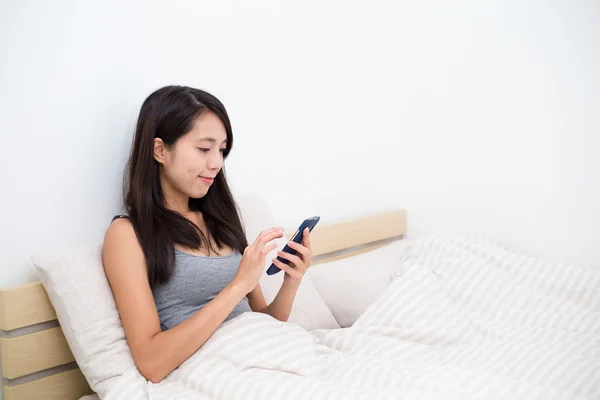 Frau im Bett benutzt Handy — Stockfoto