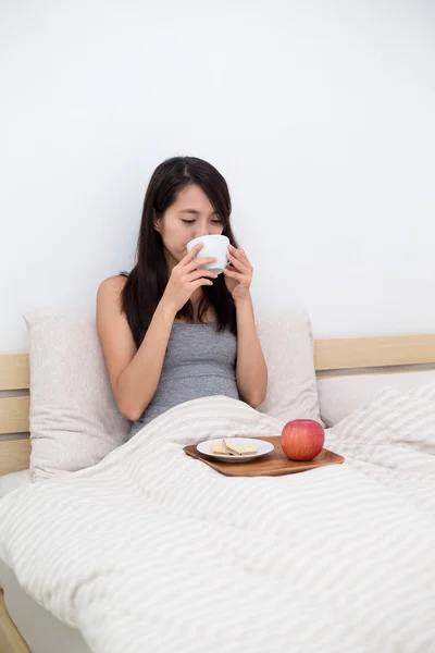 Frau frühstückt morgens im Bett — Stockfoto