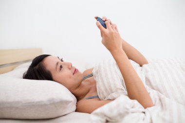 Cep telefonu kullaranarak yatakta kadın