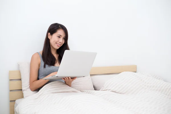 Женщина с помощью ноутбука и сидя на кровати — стоковое фото